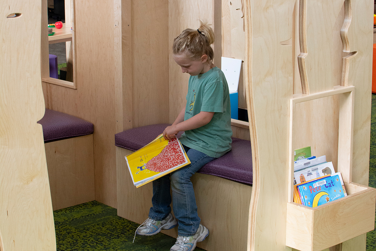girl reading in a tree house play area